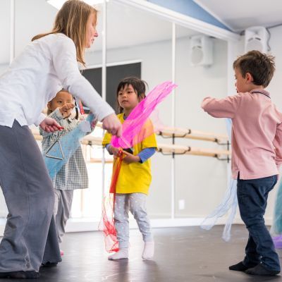 boy in pink top, girl in yellow top, girl in blue dress and girl in pink leggings with scarves